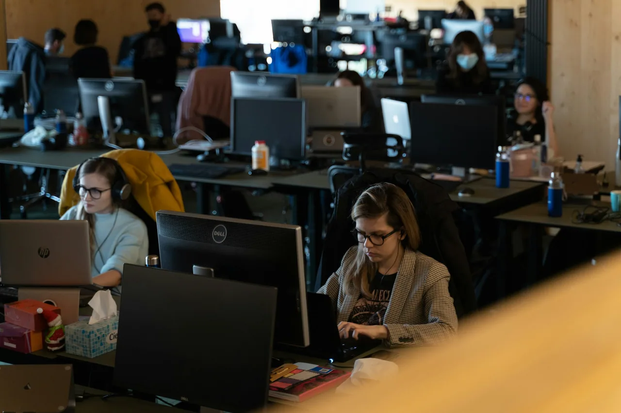 A busy newsroom work floor with people at their desks