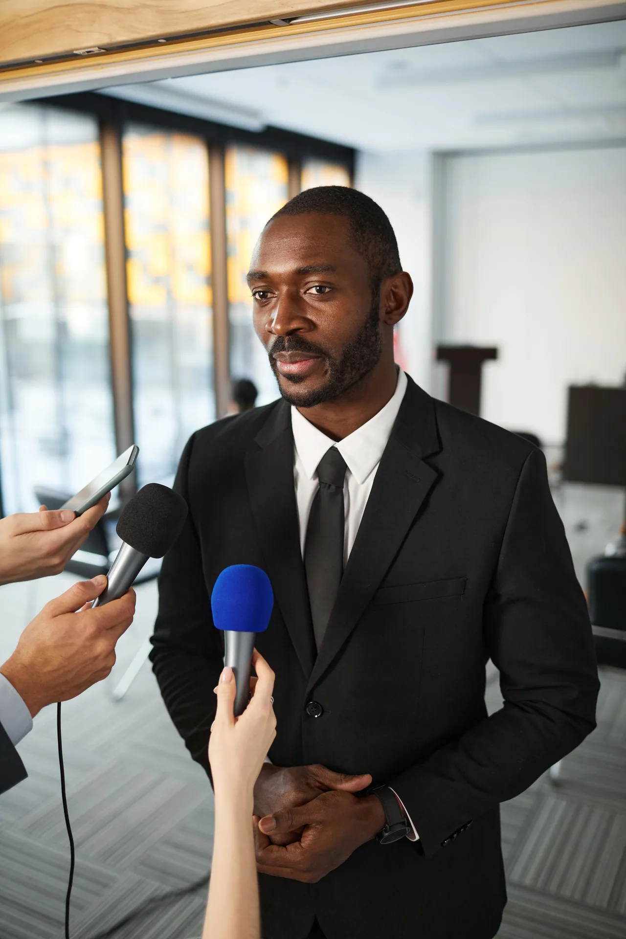Journalists holding unbranded microphones and a phone during a press interview